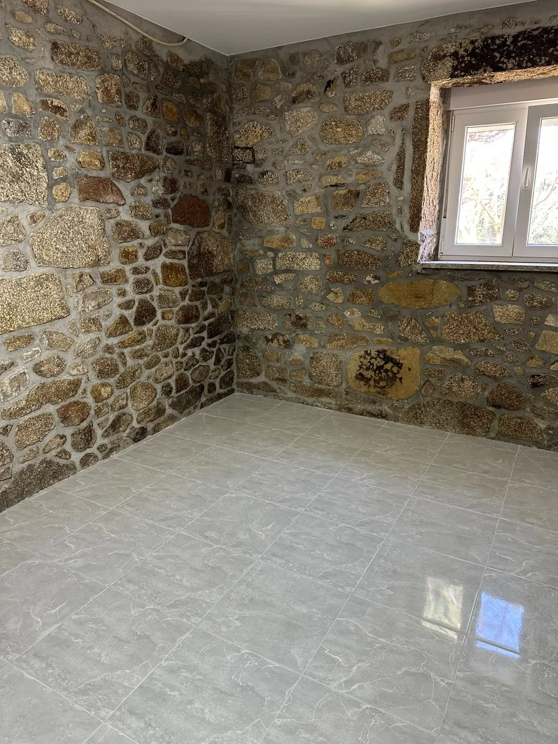 Parede interior em pedra e paredes brancas num trabalho da Vivaf