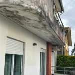 Pintura degradada na parte inferior de uma varanda antes da intervenção